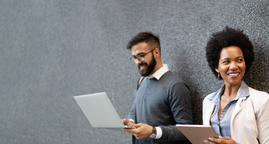 Two colleagues reviewing a laptop and tablet