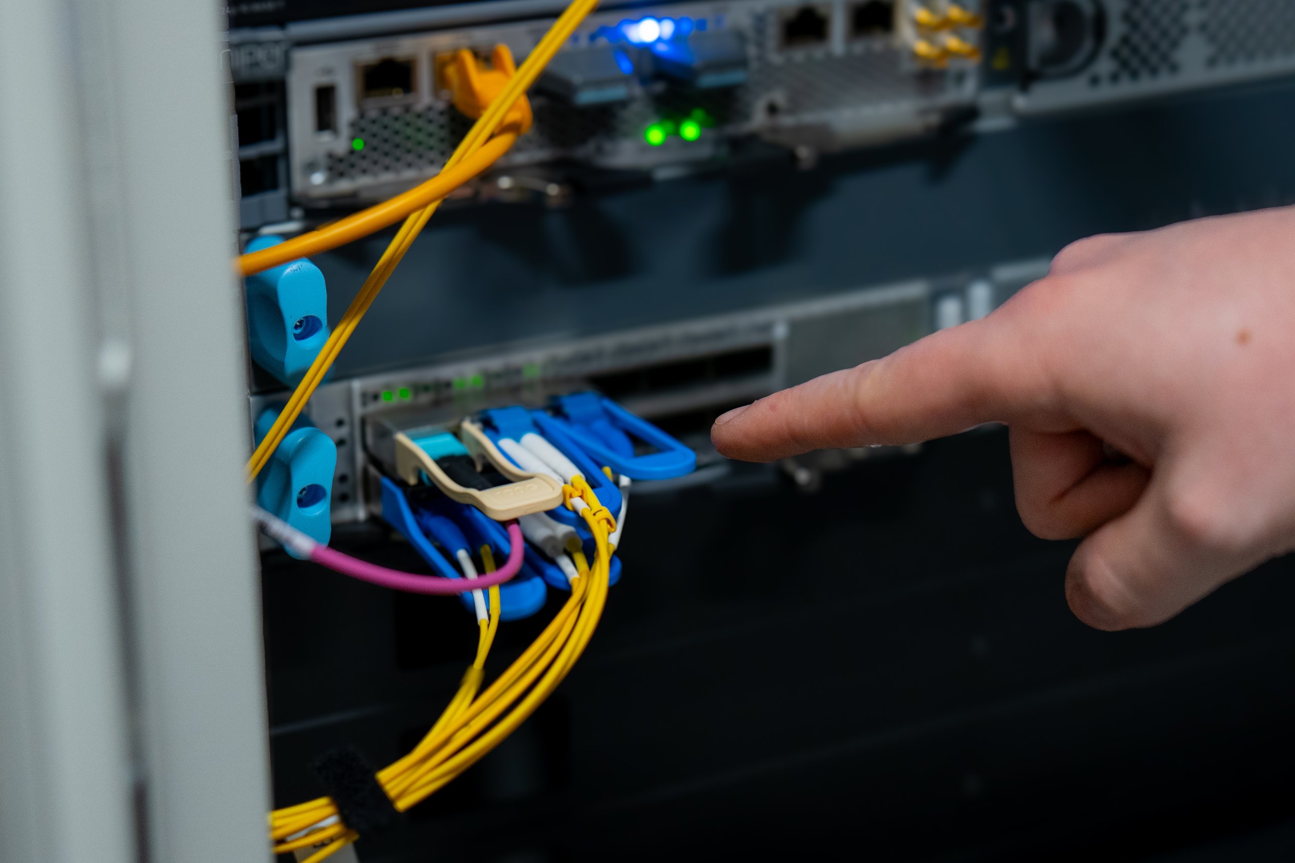 Engineer pointing at a fibre connection on a network switch