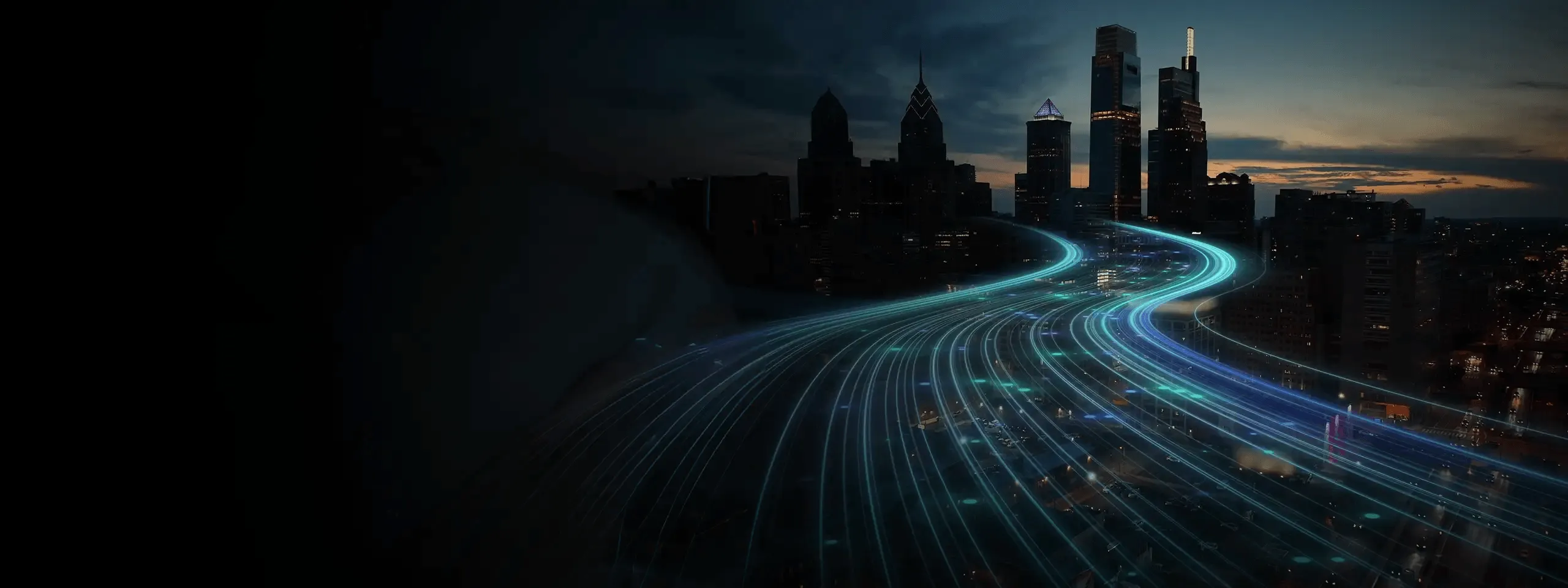 Light trail on a dark highway toward a city skyline