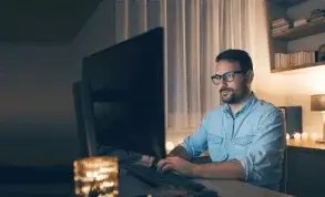 Person working at dual monitors in a dimly lit workspace