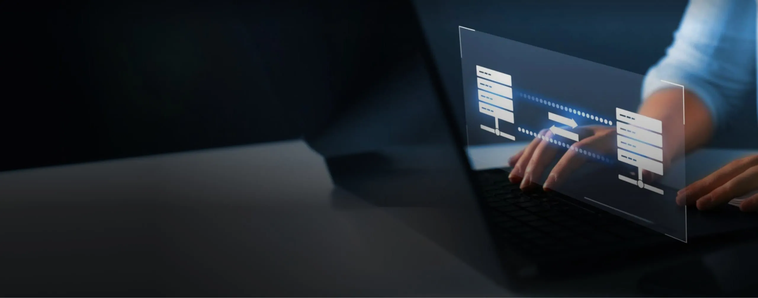 Hands typing on a laptop in a dark workspace