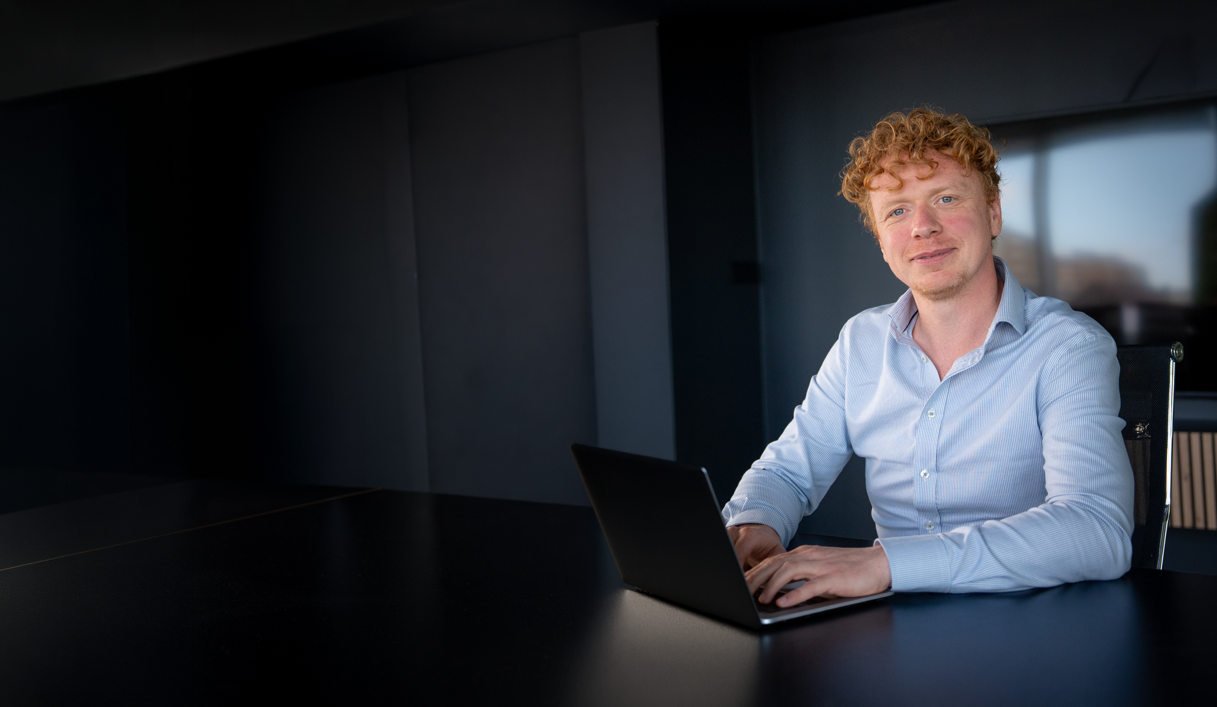 Hyve colleague in a light shirt against a dark background