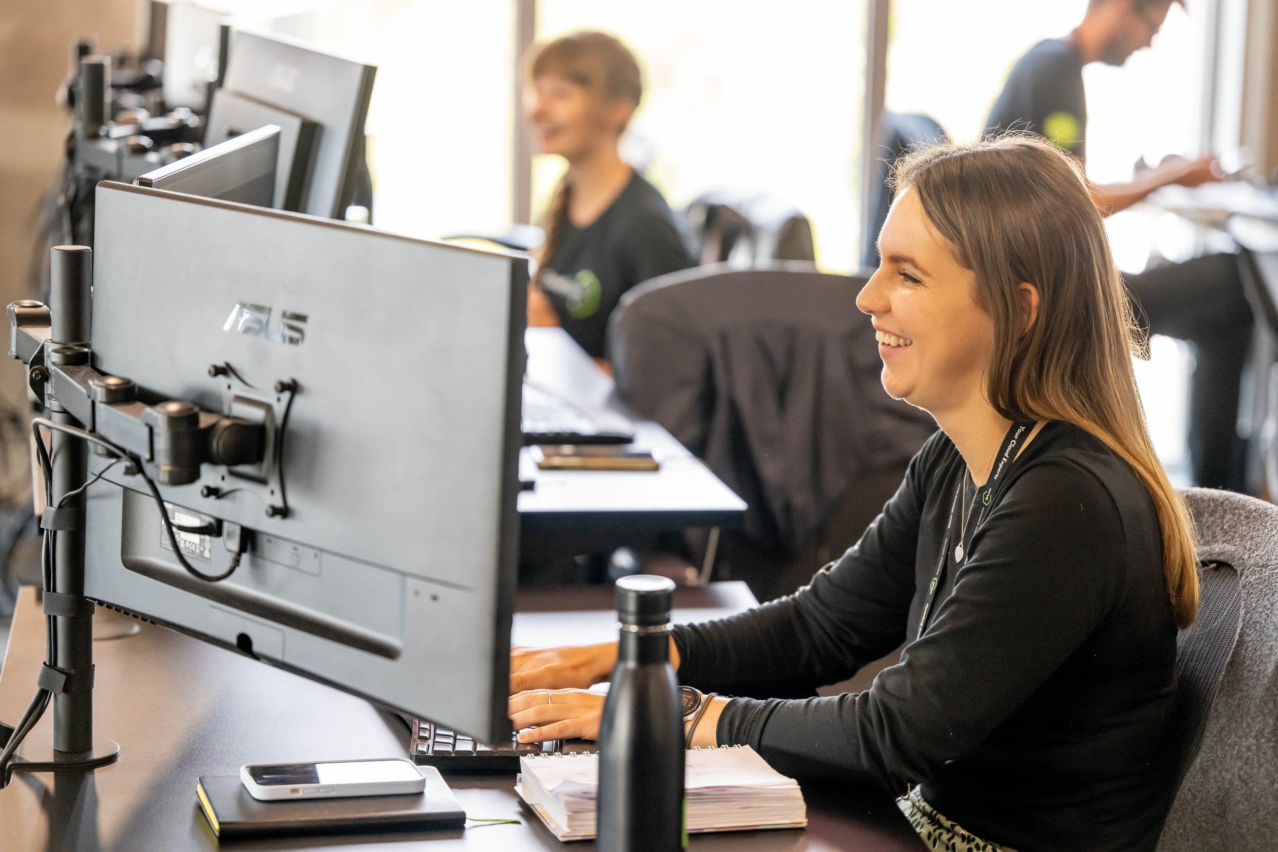 Colleague smiling at a dual-monitor desk