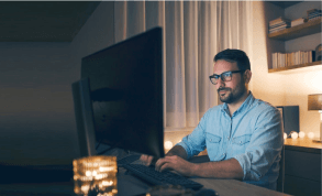 Man working in front of computer screen in a dark room