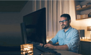Man working in front of computer screen in a dark room